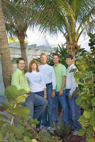 casual outdoor family portrait at their beach home by palm tree